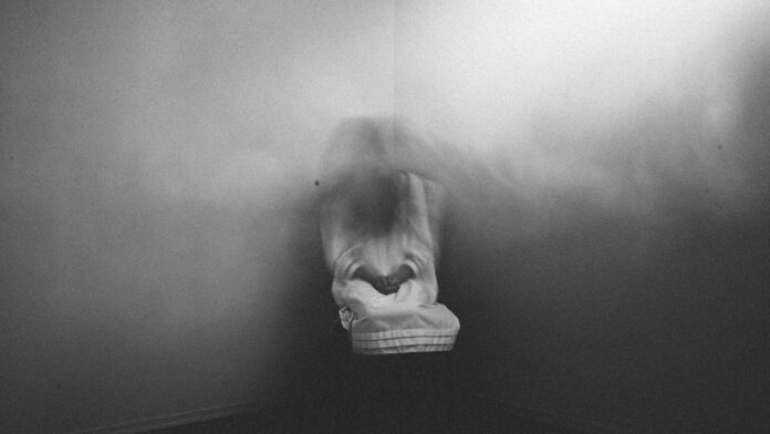 Scary ghost girl sitting in foggy haunted corner of house